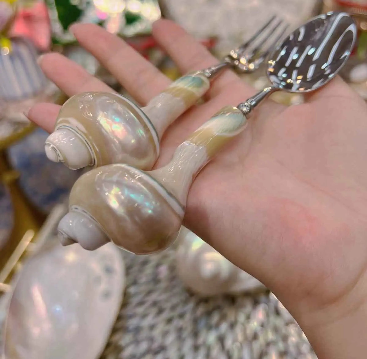 Conch shell handle details on a spoon and fruit fork held in one hand