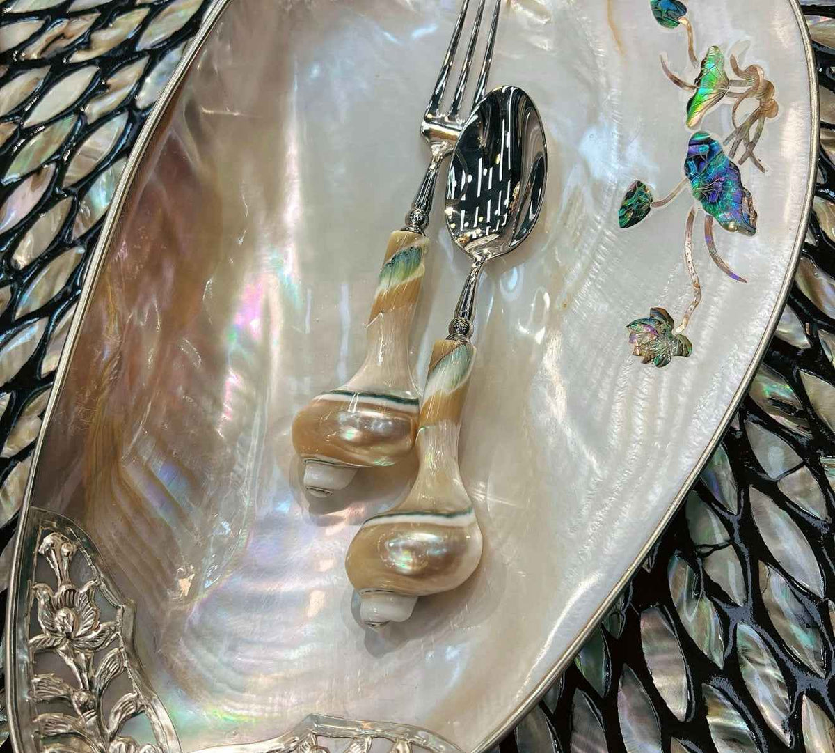 Shell-handled spoon and fruit fork displayed on a mother of pearl tray
