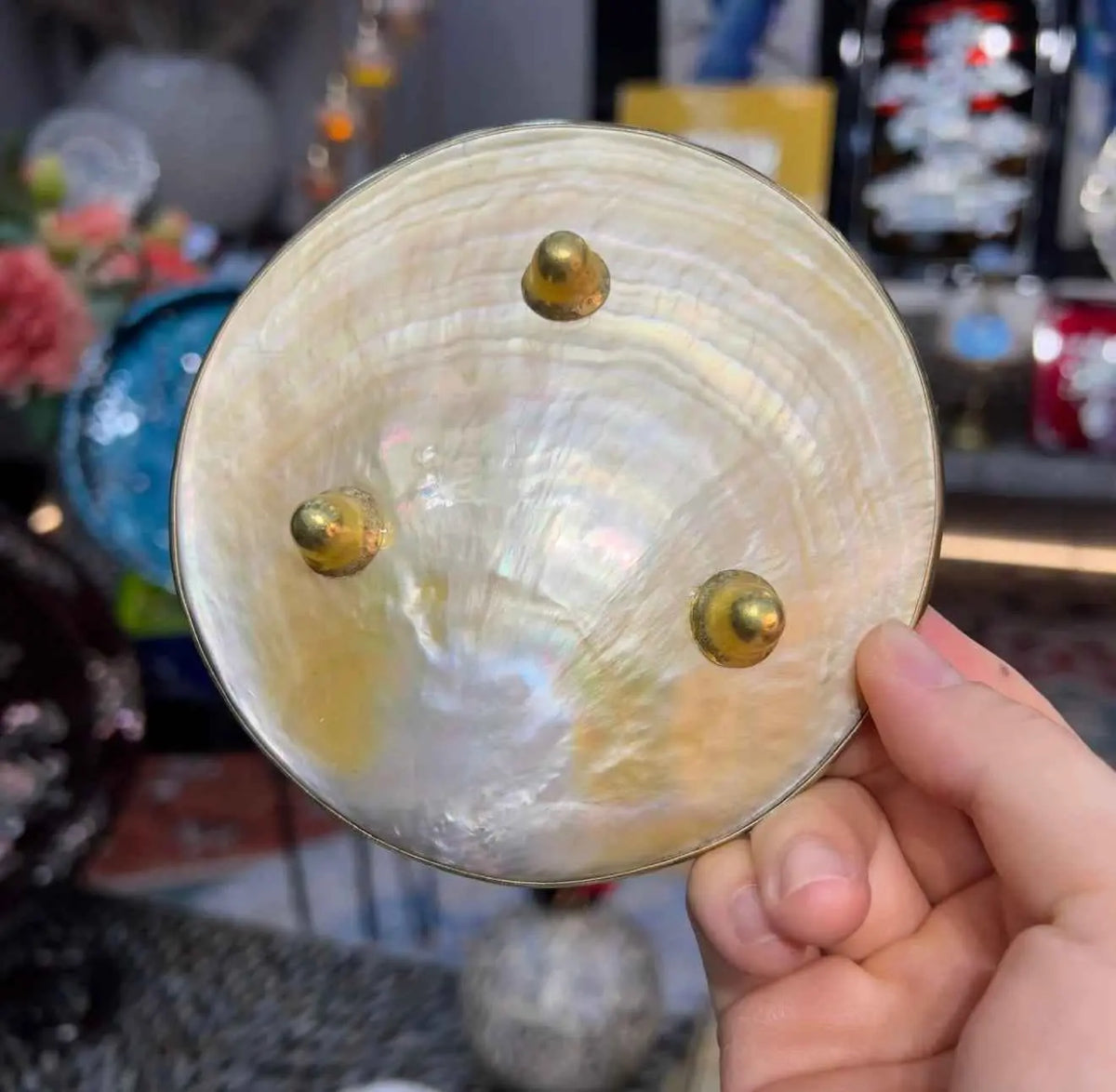 Underside of a shell dish showing three gold-tone feet