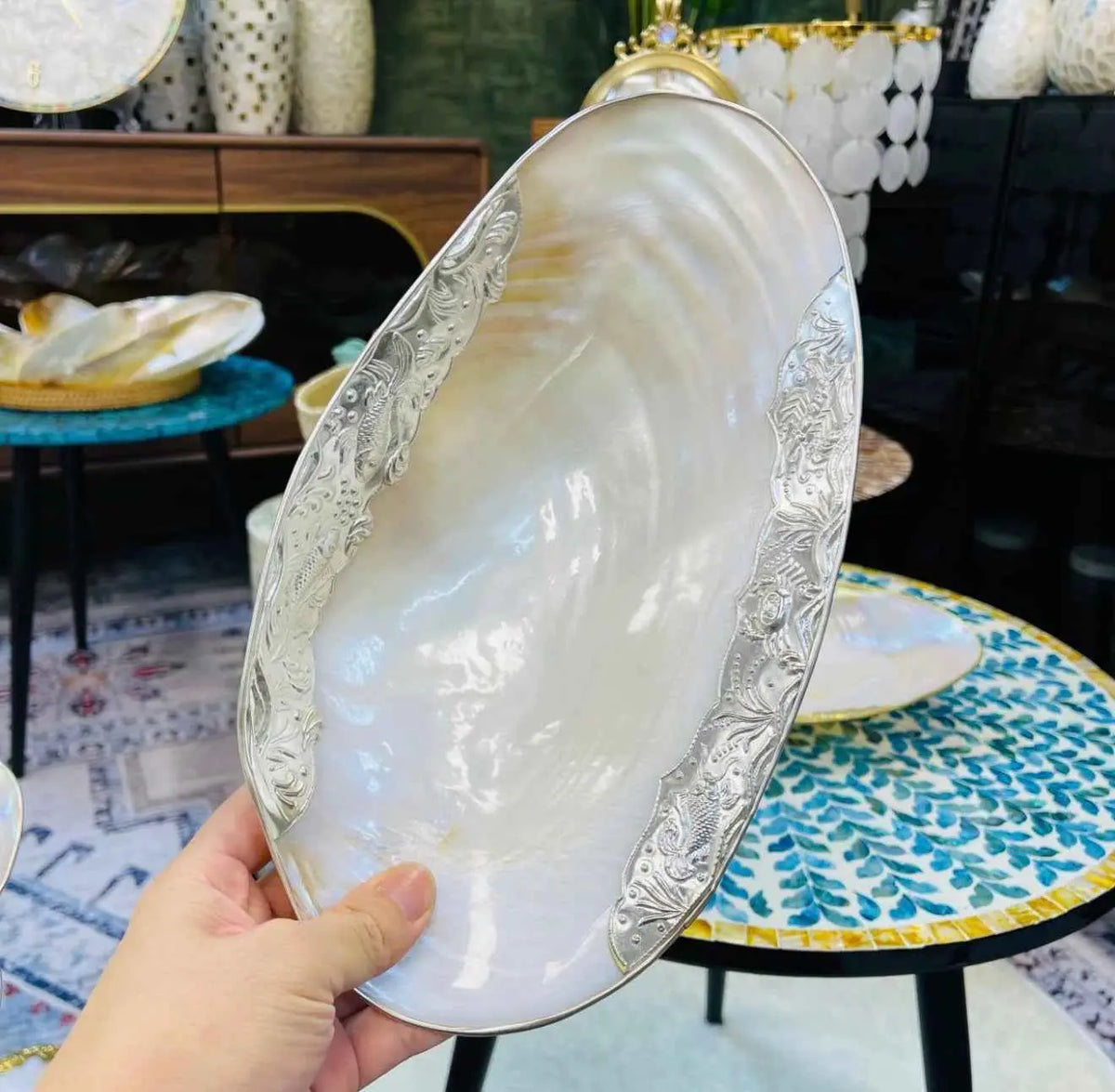 Hand holding a silver-edged iridescent shell tray