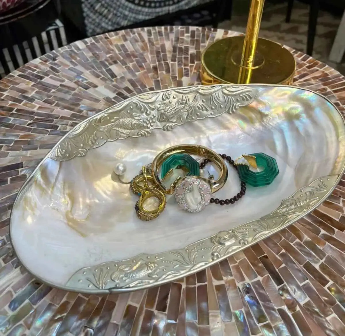 Natural shell catchall tray holding rings on a patterned table