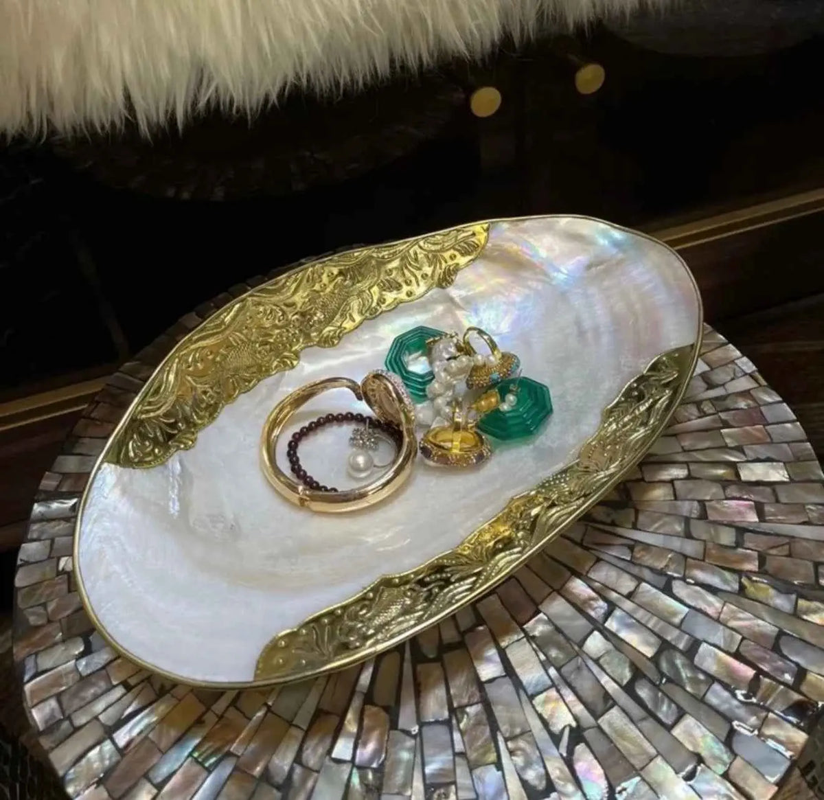 Gold-edged shell tray displaying rings and jewelry