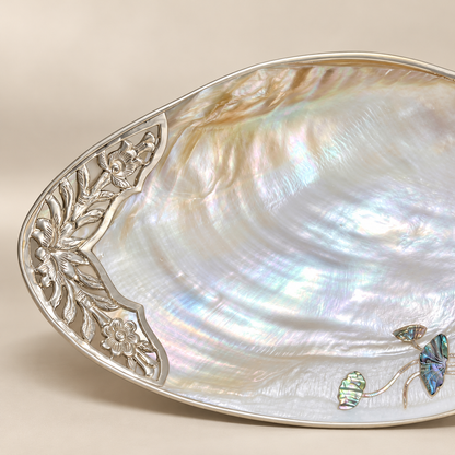 Close-up of natural mother-of-pearl iridescence and floral metalwork on a large shell tray