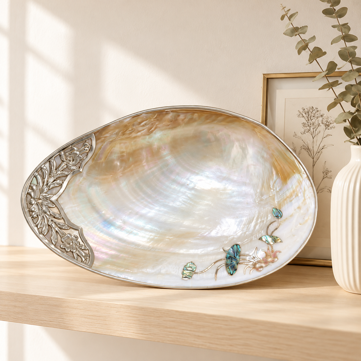 Mother-of-pearl shell tray styled on a pale wood shelf with botanical decor