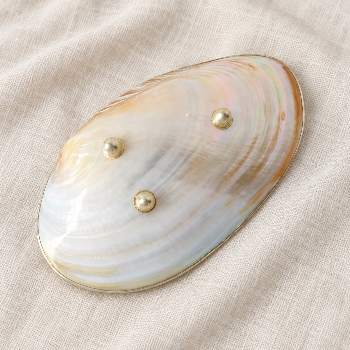 Underside of the natural mother-of-pearl tray showing three round metal feet