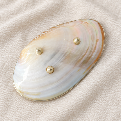 Underside of the natural mother-of-pearl tray showing three round metal feet