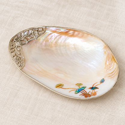 Angled view of a mother-of-pearl shell tray with lotus inlay on ivory linen